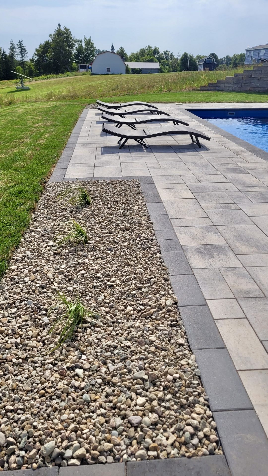 Poolside loungers on patio near garden and building