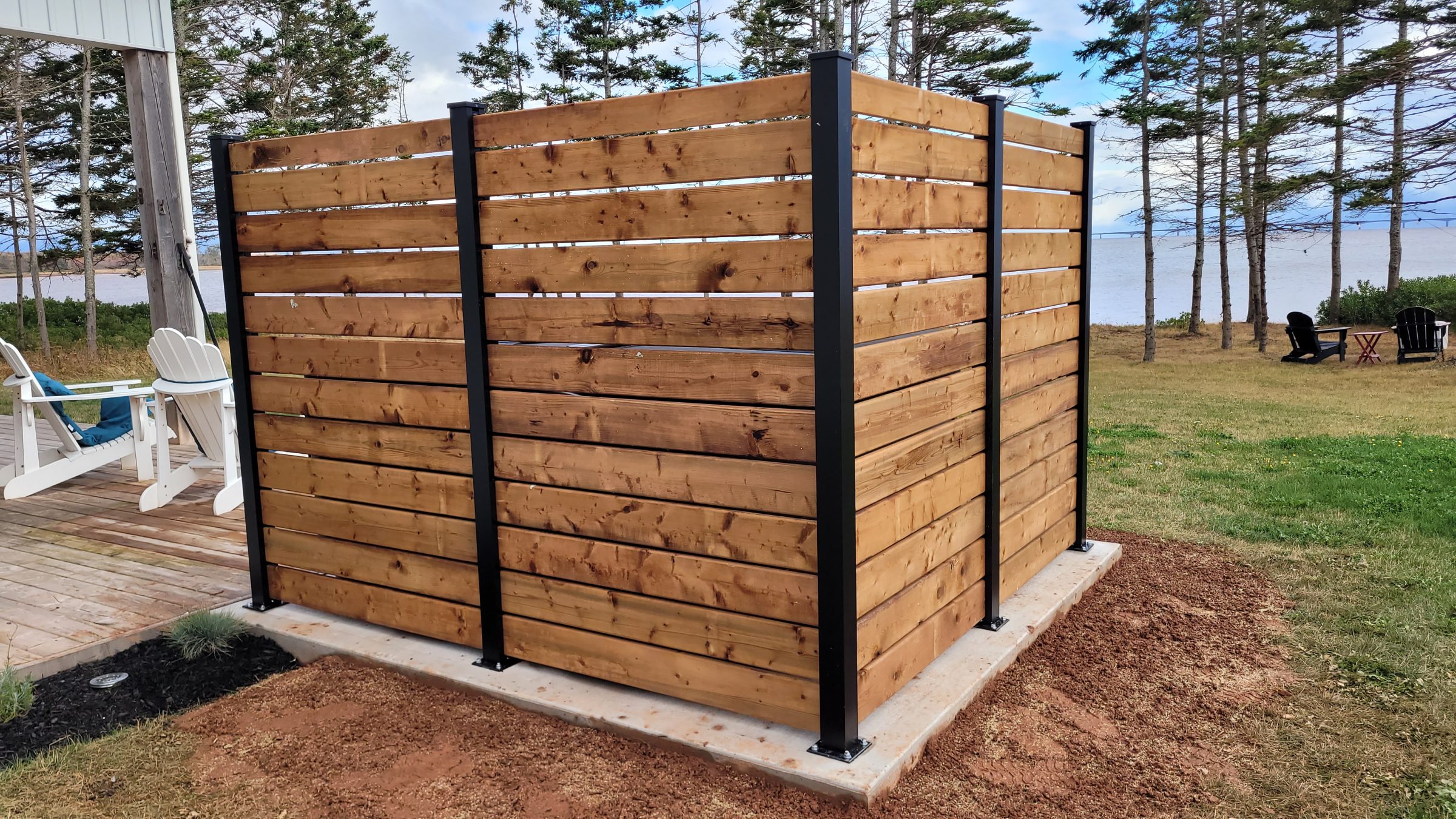 Wooden outdoor shower enclosure by lakeside garden