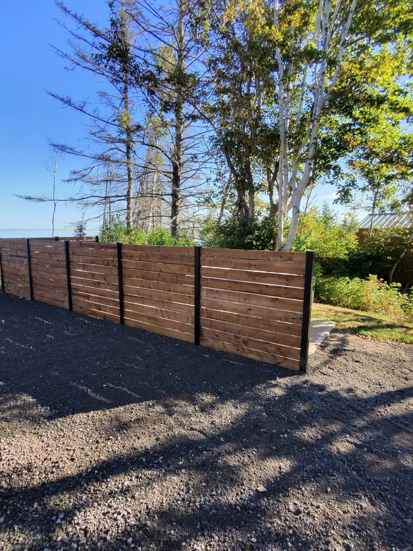 Wooden fence with trees and blue sky background.