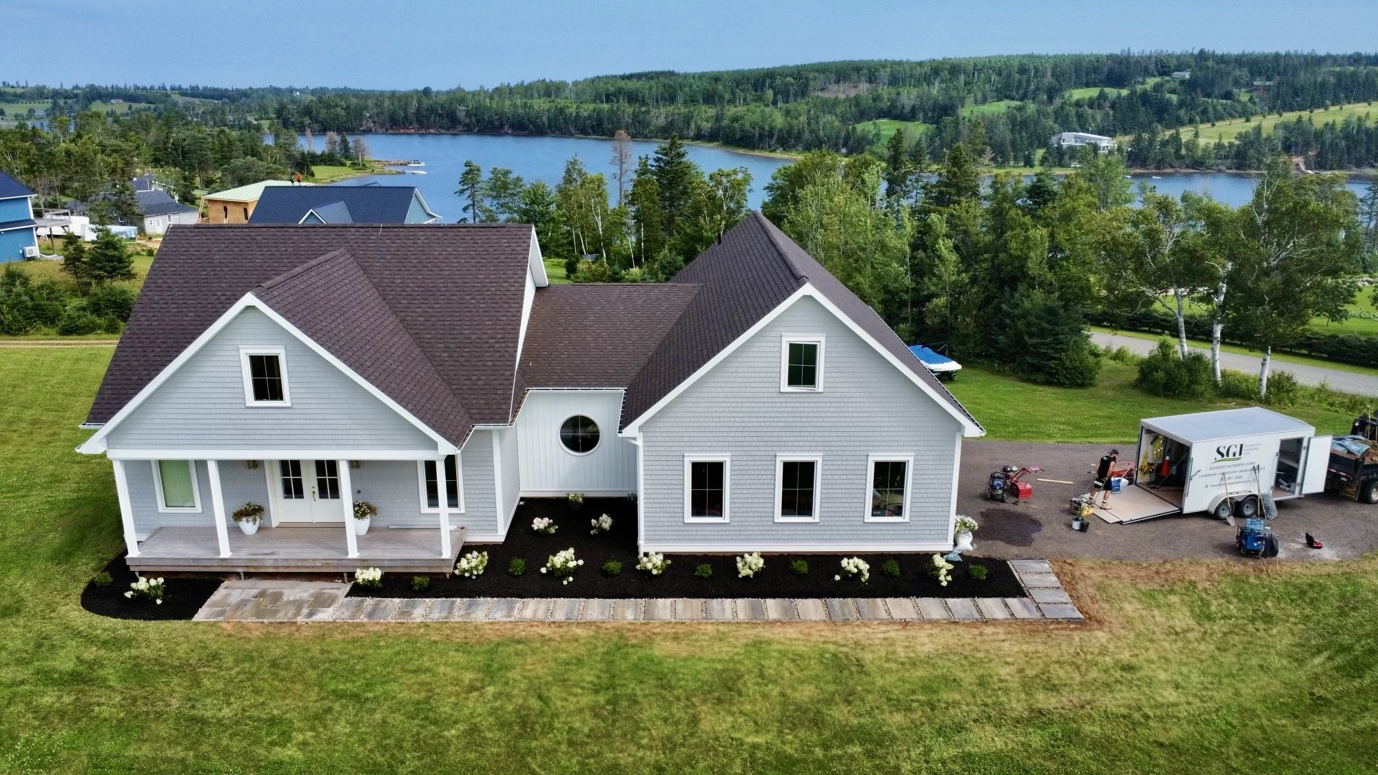 Aerial view of modern home near lake and trees.