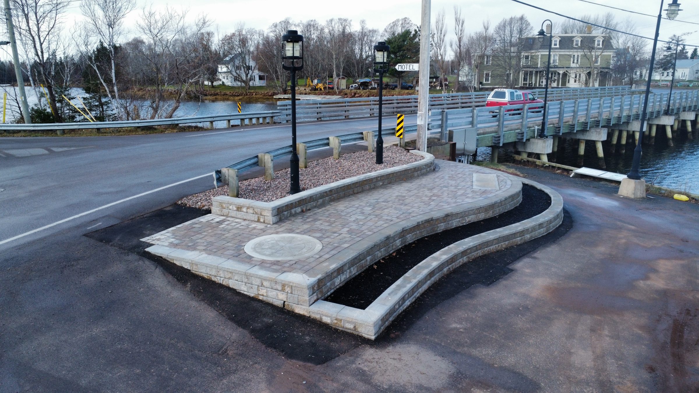 Stone pathway near bridge with streetlights and water.