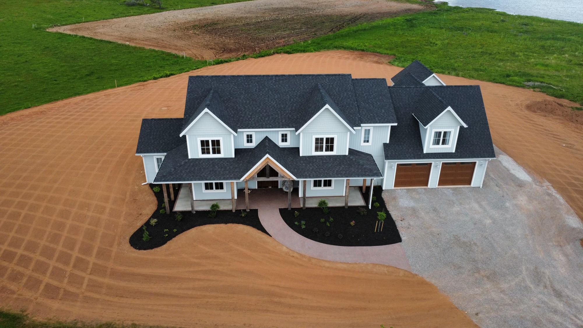 Aerial view of large modern house on dirt plot.