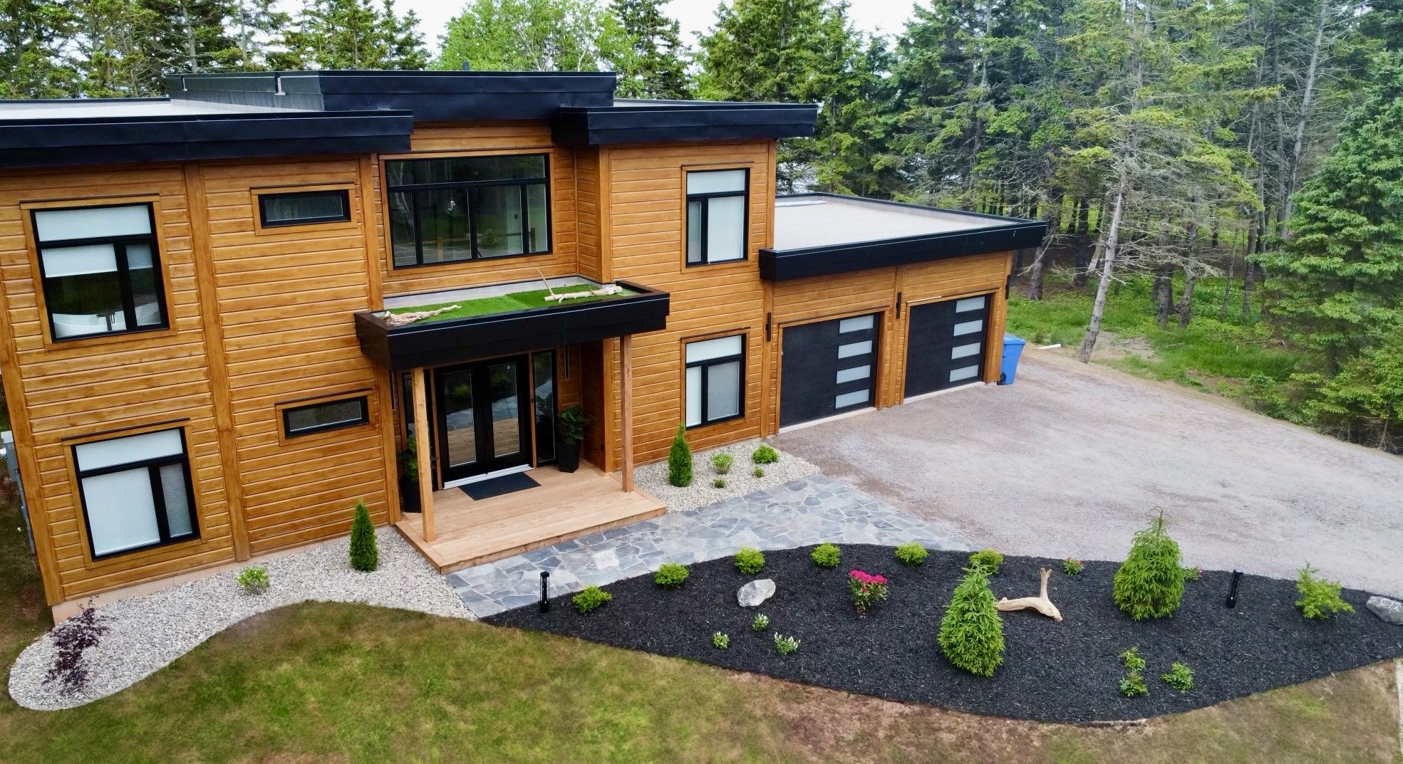 Modern wooden house with landscaped yard and driveway.