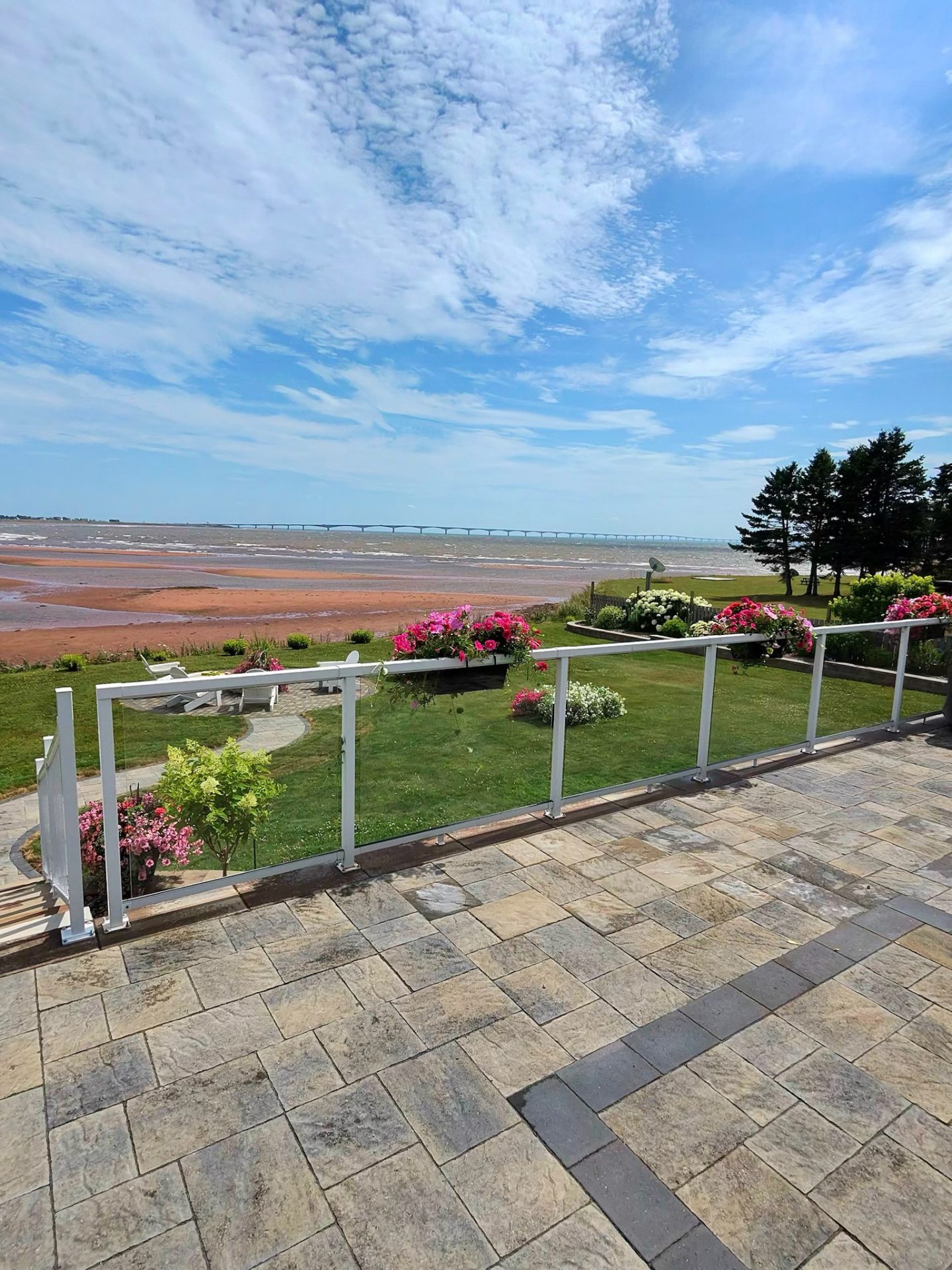 Seaside garden view with bridge and blue sky.