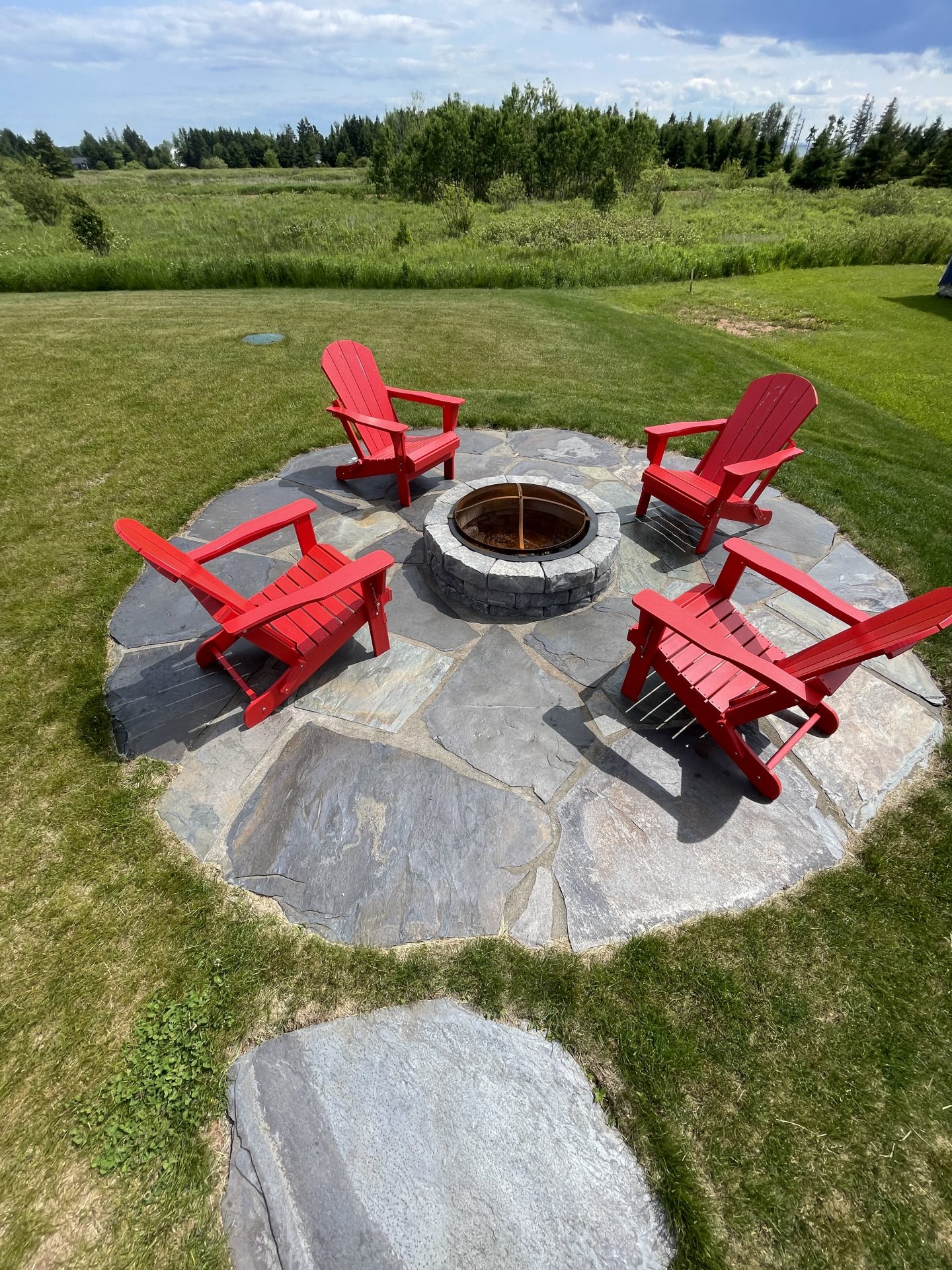Red chairs around outdoor stone fire pit.