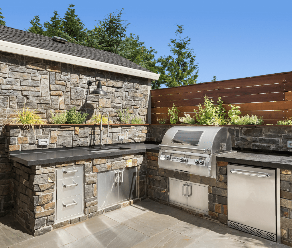 Outdoor kitchen with stone design and stainless appliances.