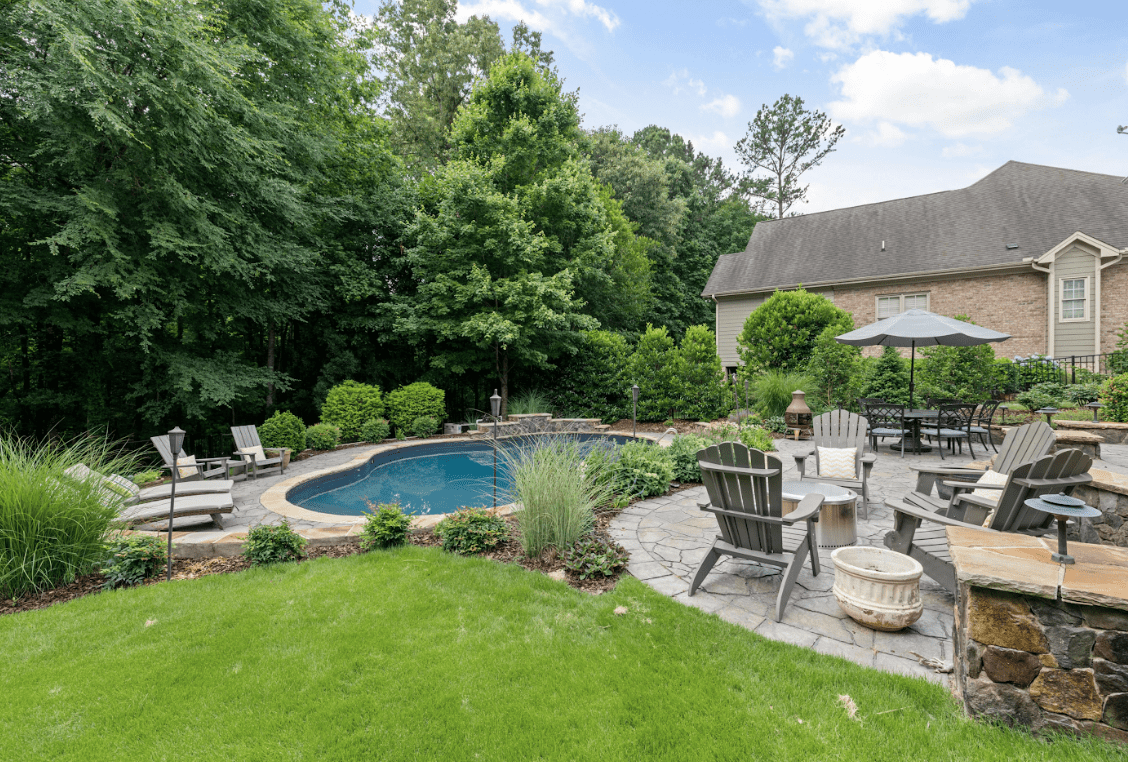 Backyard pool and patio with lush greenery.